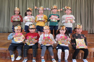 写真：キラキラの冠をかぶり誕生カードと一緒に記念撮影の2月生まれの子ども達